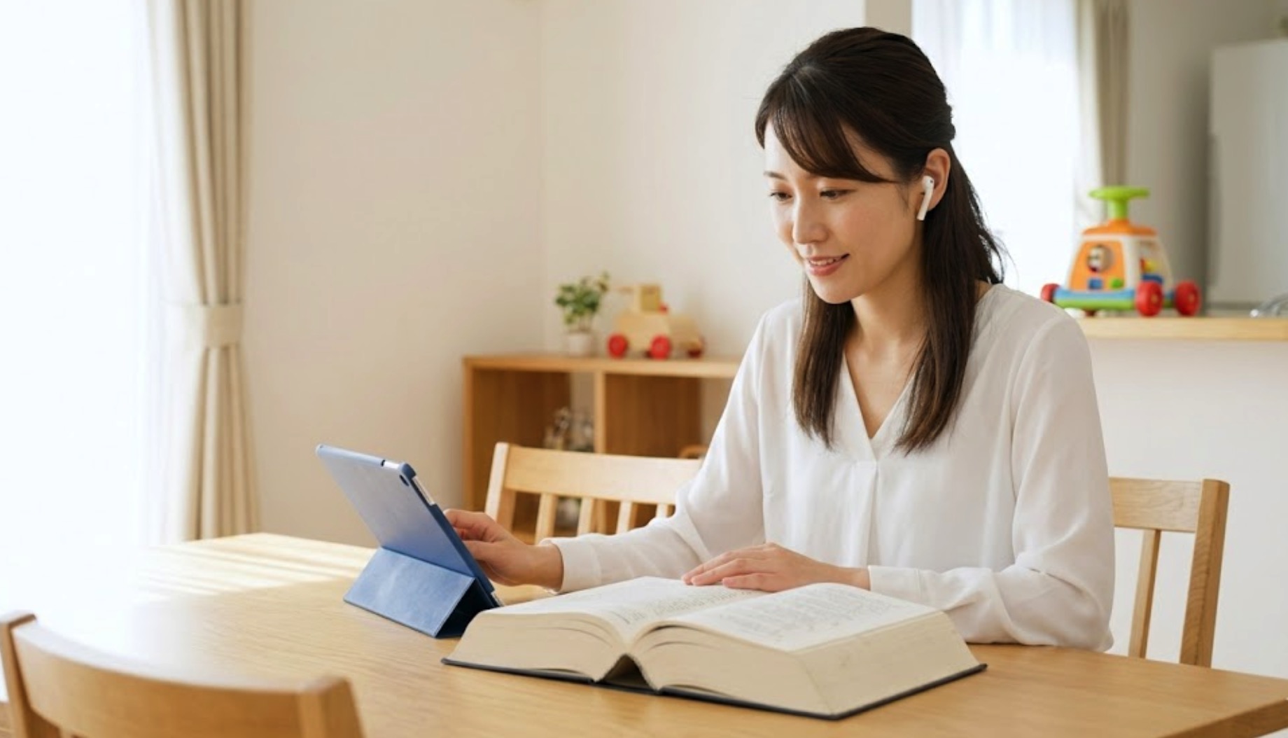 宅建の独学に取り組む主婦が自宅ダイニングでタブレットとテキストを使いスキマ時間に勉強する様子